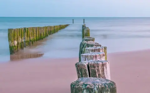 Drewniane pale tworzą ścieżkę wzdłuż plaży, prowadzącą w stronę morza. To idealne miejsce na spacer, odkrywając kąty rybackie trasę.
