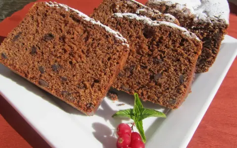 Rebanadas de bizcocho de colacao con trocitos de chocolate, espolvoreado con azúcar glas y decorado con grosellas y menta.