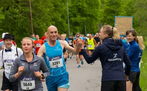 Glada löpare hejar på varandra under sista veckan innan halvmarathon. En man ger en high five till en kvinna.