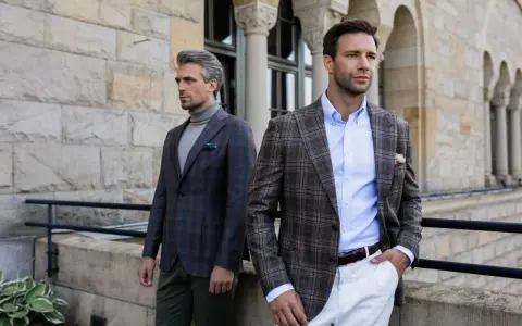 Dwóch eleganckich mężczyzn w marynarkach w kratę. Jeden ma szary golf, drugi błękitną koszulę. Stylowy mankiet co to?