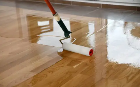 Application d'une couche de vitrificateur sur un parquet en bois. Le temps de séchage entre 2 couches est crucial pour un résultat parfait.