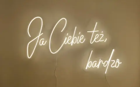Neonowy napis "Ja ciebie też bardzo" rozświetla ścianę, tworząc ciepłą atmosferę.