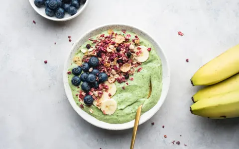 Grön smoothiebowl med blåbär, banan och granola. Ett perfekt proteinrikt mellanmål för en energifylld dag.
