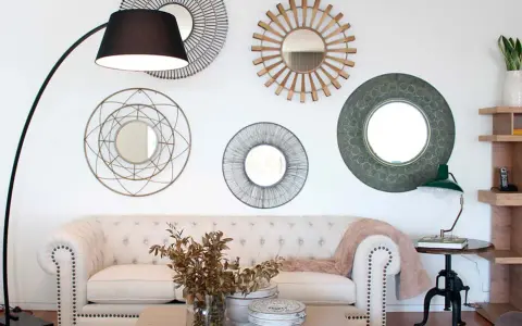 Salón moderno con sofá blanco, lámpara de pie y varios espejos decorativos que siguen principios de feng shui para atraer energía positiva.