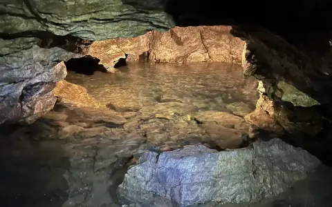 Wnętrze jaskini Radochowskiej z krystalicznie czystą wodą odbijającą skalne ściany.