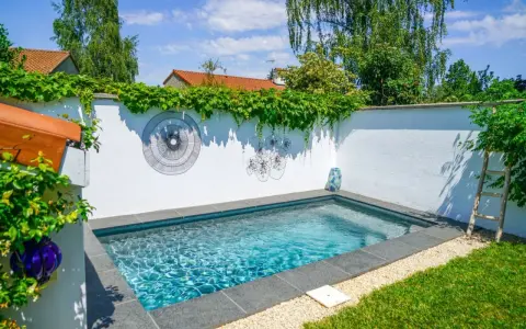 Petite piscine bleue dans un jardin verdoyant, décorée d'art mural. Un projet de permis de construire piscine réussi.