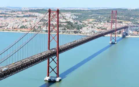El puente 25 de Abril en Lisboa, con sus icónicas torres rojas, cruza el río Tajo. ¿Cuanto mide el puente de Lisboa? Es un coloso de ingeniería.