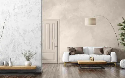 Un salon moderne avec un mur texturé en enduit décoratif, un canapé blanc, une table basse en bois et une plante verte.