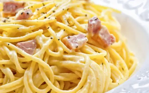 Un plato de pasta cremosa con trozos de panceta y pimienta negra molida, una auténtica carbonara original.