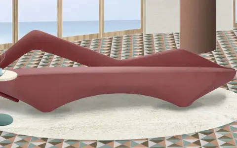 A pink velvet sofa with a unique curved design sits on a cream rug in a room with a geometric tiled floor and a view of the ocean.