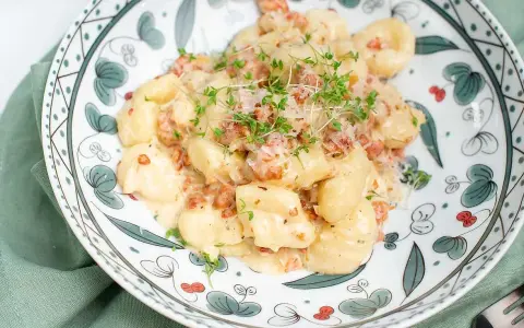 Krämiga gnocchi med salsiccia, toppade med riven ost och färska örter. En härlig rätt som passar perfekt för en mysig middag.