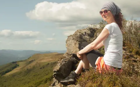 Kobieta odpoczywa na szczycie, podziwiając widok na Bieszczady. To miejsce, które warto zobaczyć, oferuje niezapomniane krajobrazy.