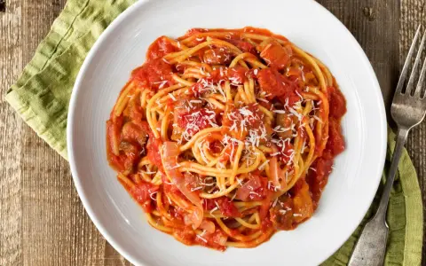 Spaghetti al pomodoro con pezzi di carne e cipolla, uno dei classici sughi per pasta, spolverati di parmigiano.