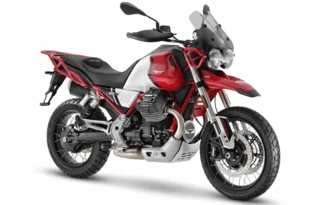 Czerwono-biały motocykl Moto Guzzi V85 TT z czarnym siedzeniem i akcentami, gotowy na przygodę.