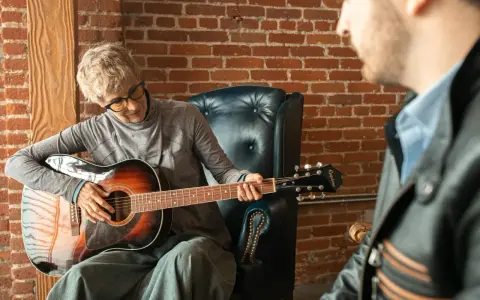 Kobieta gra na gitarze w szkole muzycznej dla dorosłych. Lekcja z nauczycielem.