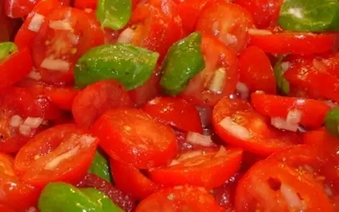 Frischer Tomatensalat mit Zwiebeln und Basilikum, bereit für ein leichtes Tomatensalat Dressing.