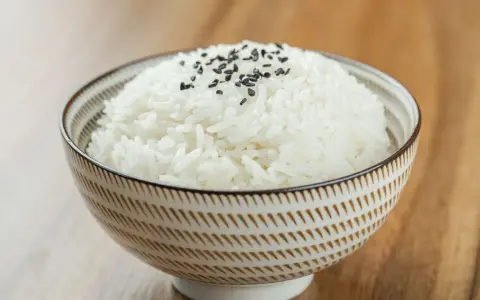 Miseczka puszystego ryżu basmati, posypana czarnym sezamem. Idealny przykład, jak ugotować ryż basmati.