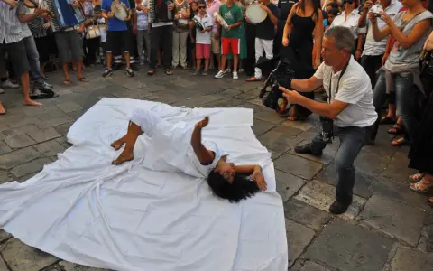 Danza contemporanea durante la festa patronale Galatina. Un performer si muove su un telo bianco, ripreso da un operatore.