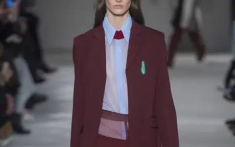 Modella con blazer bordeaux, camicia azzurra e cravatta rossa. Il bordeaux dona un tocco di eleganza sofisticata.