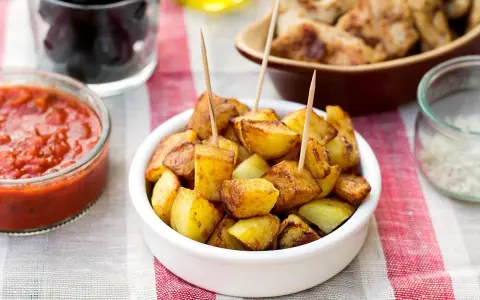 Patatas bravas dorées, servies avec une sauce tomate épicée et des olives. Un délice pour l'apéro !