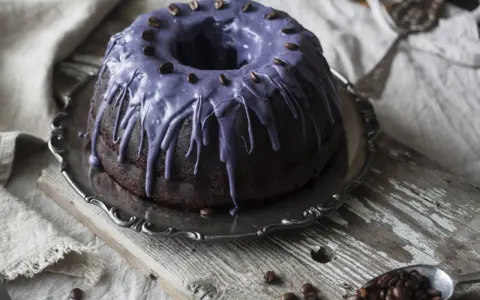 Mörk chokladkaka med lila glasyr och kaffebönor, perfekt för ett chokladkaka recept.