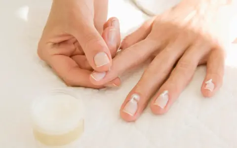 Application de crème pour hydrater la peau sèche autour des ongles.
