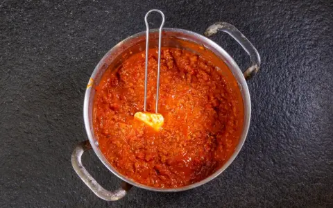 Herzhaftes Ragu in einem Topf, bereit für ein köstliches Ragu Rezept. Ein Löffel mit Butter liegt darin.