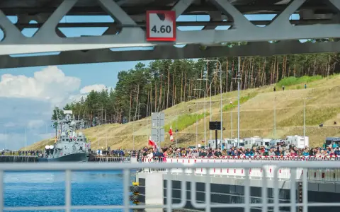 Uroczyste otwarcie przekopu Mierzei Wiślanej. Na wodzie okręt, na brzegu tłumy widzów.