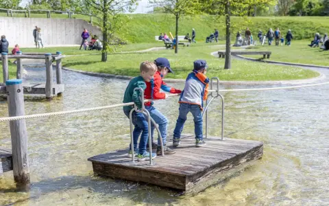 Drei Jungen auf einem Floß im Wasserspielplatz, der an ein Schiffshebewerk erinnert.