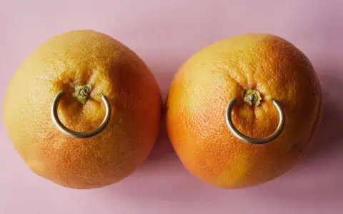 Dwa grejpfruty z kółkami imitującymi, ile goi się kolczyk w sutku.