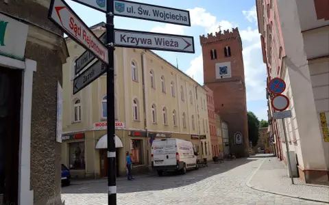 Ulica z wieżą i drogowskazami do Sądu Rejonowego, Krzywej Wieży i Zamku. Odkryj mało znane miejsca na Dolnym Śląsku.