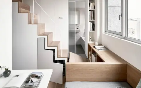 Monolocale con soppalco: scala in legno e bianco, bagno con doccia, scrivania e letto integrati.