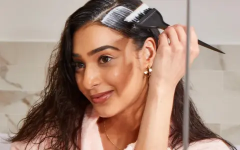 Mujer aplica producto para aclarar pelo castaño oscuro sin decolorar.