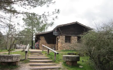 Mesones Riopar: acogedor bar-restaurante de piedra y madera en un entorno natural. Escaleras de acceso y mesas exteriores invitan a disfrutar.