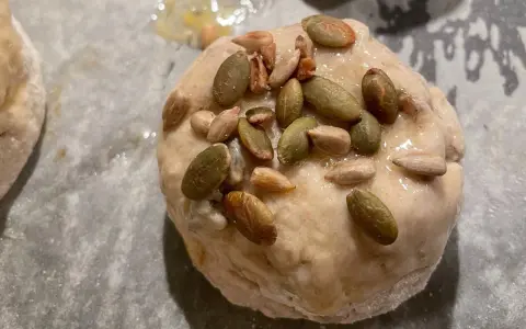 En glutenfri fralla med pumpa- och solrosfrön på en bakplåt.