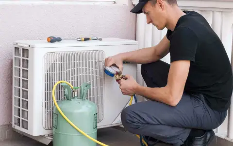 Técnico recargando gas aire acondicionado casa. Manómetro y tanque verde conectados a la unidad exterior.
