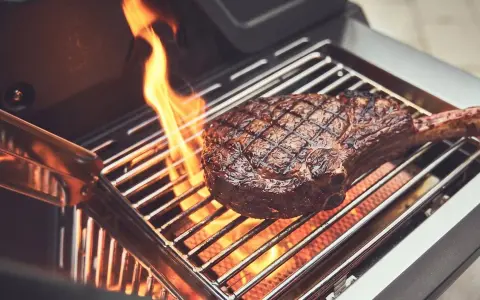 Ein saftiges Steak wird auf einem Gasgrill gegrillt, Flammen züngeln empor.