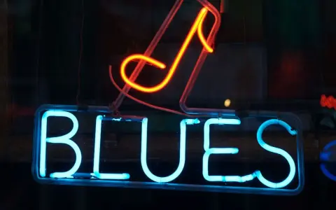 Néon bleu lumineux "BLUES" avec une note de musique rouge orangé au-dessus. L'ambiance parfaite pour une soirée blues.