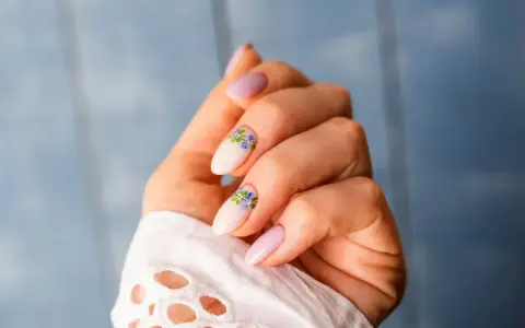 Delikatne, jasnoróżowe paznokcie z kwiatowym zdobieniem. Nawet przy łamliwych paznokciach można stworzyć piękny manicure.