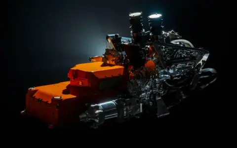 Un vistazo a los futuros motores F1 2026: un complejo sistema híbrido con componentes naranjas y metálicos, listo para la velocidad.