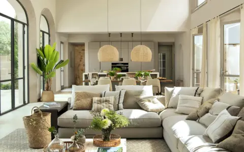 Salón y cocina integrados con **estilo moderno decoración**. Sofá modular beige, cestas de mimbre, plantas y lámparas de fibras naturales.