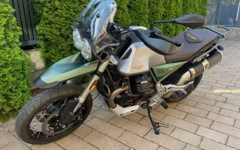 Zielony motocykl Moto Guzzi V85TT z silnikiem V, gotowy na przygodę.