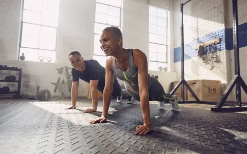 Coppia sorridente in palestra, che fa flessioni. Lo sport è un valido alleato contro la depressione, un modo per ritrovare energia e benessere.