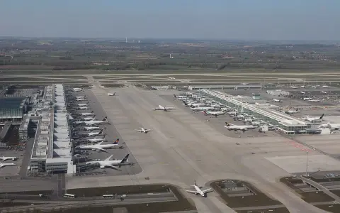 Lotnisko w Monachium tętni życiem. Wiele samolotów stoi przy terminalach, inne kołują po płycie lotniska.