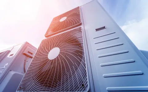 Pompa ciepła 8kw na ile metrów? Widok z dołu na kilka jednostek klimatyzacyjnych na tle błękitnego nieba.