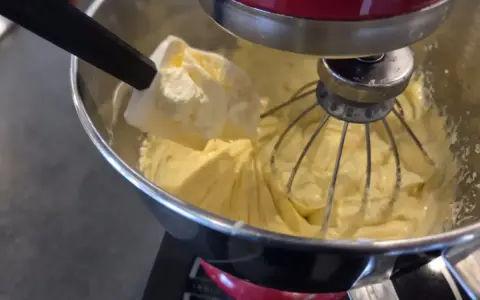 Préparation d'une crème onctueuse pour savoir que faire avec de la crème mousseline. Une spatule ajoute une touche finale à la préparation.