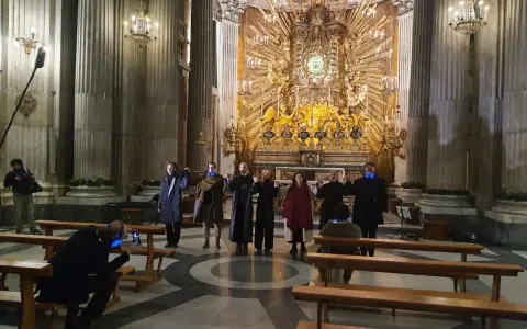A group of people in a church, some holding hands, with a large golden altar in the background.