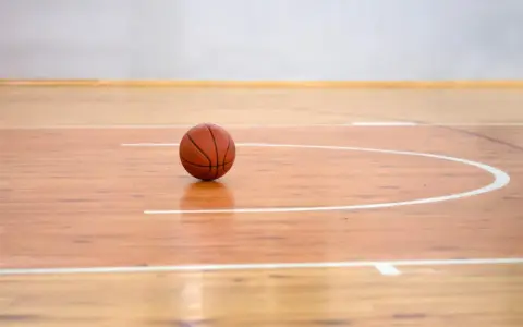 Balón de baloncesto sobre los pavimentos deportivos de madera pulida, listo para el juego.