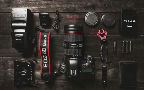 Zestaw fotograficzny: aparat Canon EOS 6D Mark II z obiektywem, lampa błyskowa, baterie i akcesoria. Podstawa aparatu fotograficznego gotowa do pracy.