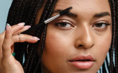 Une femme utilise une brosse pour coiffer son sourcil. La repousse d'un sourcil est une question de patience.